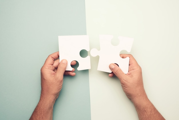 Mannenhand met grote papieren witte lege puzzelstukjes