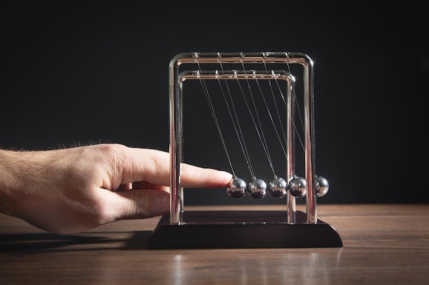 Mannenhand met Newtons wiegballen op de houten tafel