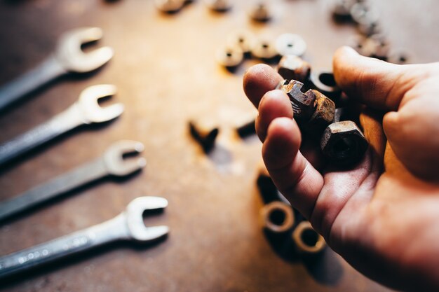 Mannenhand met oude moeren moersleutel sleutels op roestig metalen bureau intreepupil