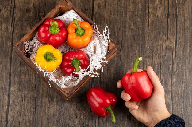 Mannenhand met rode paprika op houten oppervlak