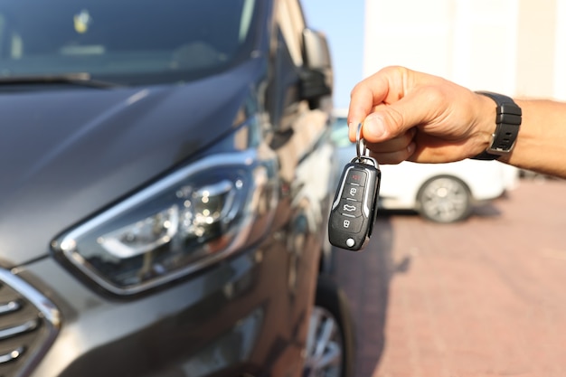 Mannenhand met sleutels in de buurt van nieuwe auto close-up. autohuur concept