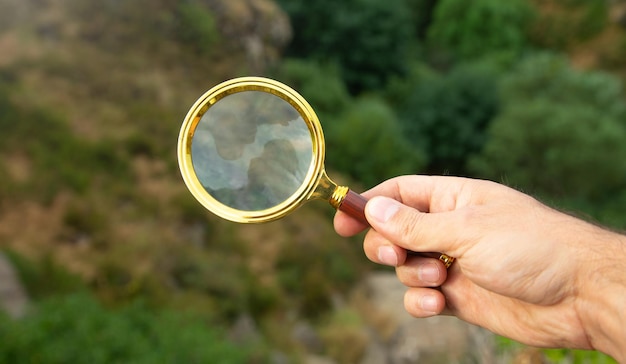 Mannenhand met vergrootglas in de buitenlucht