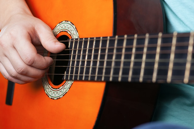 Mannenhand speelt akoestische gitaarsnaren.