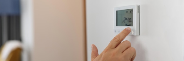 Mannenhand stelt een programmeerbare thermostaat in voor verwarming en koeling close-up apparaat regelt de