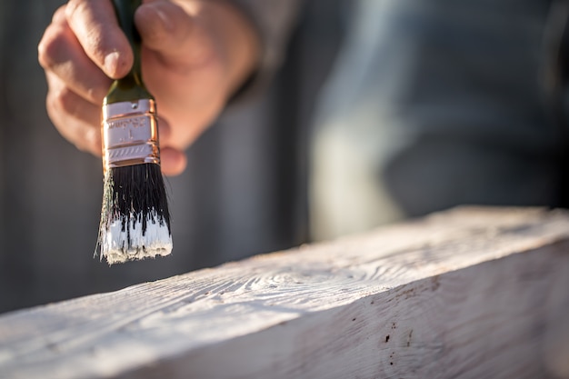 mannenhand verven met witte verf op hout