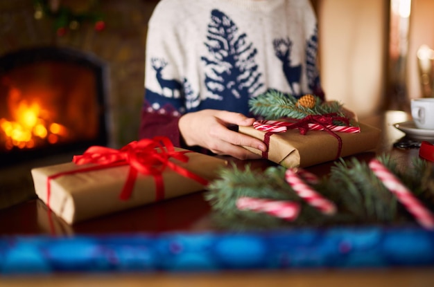 Mannenhanden houden kerstcadeau vast Man gebruikt lint groen dennenboomtakje om kerstcadeau te maken