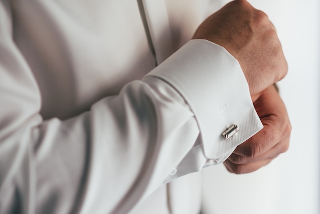 Mannenhanden op een oppervlak van een wit overhemd, mouwoverhemd met manchetknopen en horloges, close-up gefotografeerd