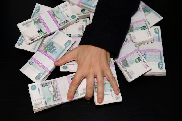 Mannenhanden reiken naar een pakje geld Een miljoen roebel op de zwarte tafel Het concept van rijkdom, succes, hebzucht en corruptie, geldzucht
