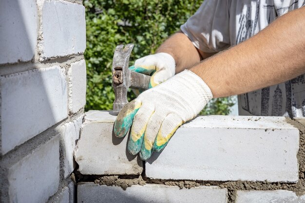 Mannenhanden repareren het metselwerk met een hamer