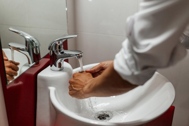 Mannenhanden wassen onder stromend water in de badkamer boven de gootsteen