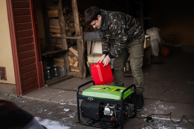 Mannenkleding in militaire jas giet benzine uit jerrycan in draagbare mobiele back-up standby-generator