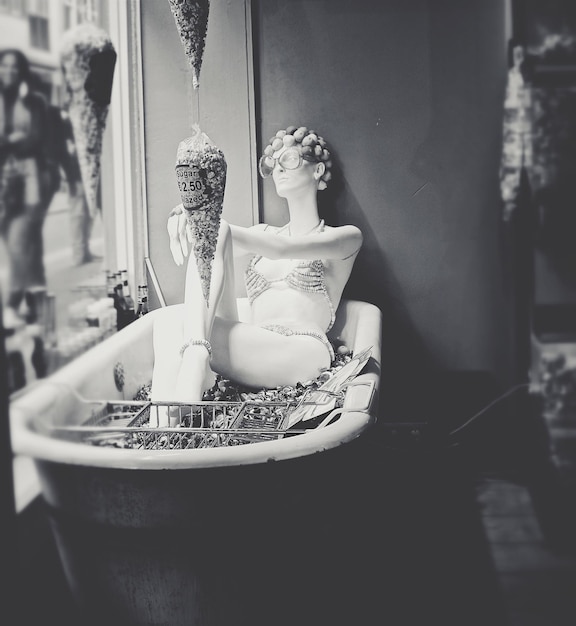 Photo mannequin in bathtub at window display in store