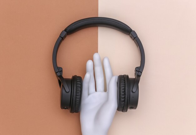 Mannequin hand met stereo koptelefoon op bruin beige achtergrond. Minimalisme concept art. Bovenaanzicht