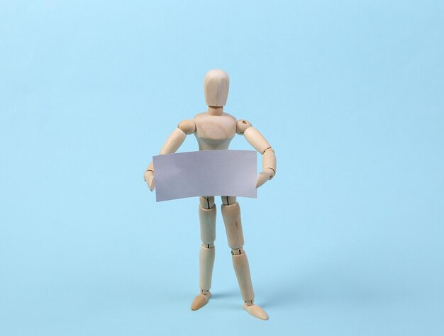 Mannequin holding up blank card on blue background