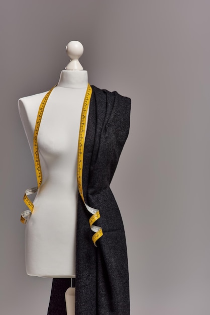 mannequin met kwaliteitsstof en meetband op grijze achtergrond mode bedrijfsconcept