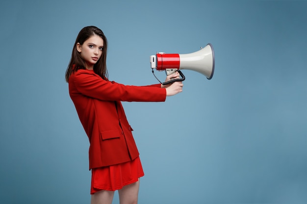 Mannequin met megafoon in de rok van het rode pakjasje mooie jonge vrouw blauwe background