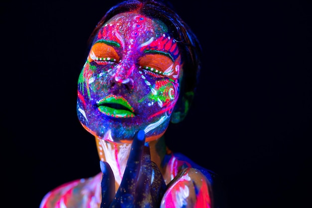 Mannequin vrouw in neonlicht, portret van mooi model meisje met fluorescerende make-up, body art ontwerp van vrouwelijke disco danseres poseren in uv, geschilderd gezicht, kleurrijke make-up, op zwarte achtergrond