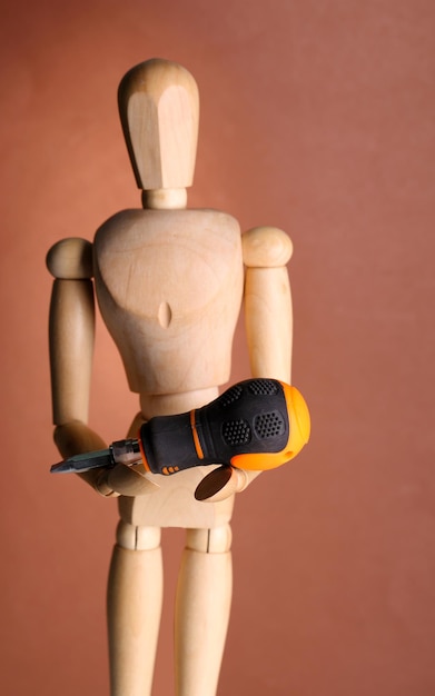 Mannequin with screwdriver on brown background