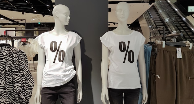 흰색 티셔츠를 입은 마네킹은 쇼핑을 위해 쇼핑몰에 퍼센트 세일 표지판이 있습니다. 판촉, 광고, 쇼핑, 블랙 프라이데이 컨셉입니다. 배경에 옷입니다.