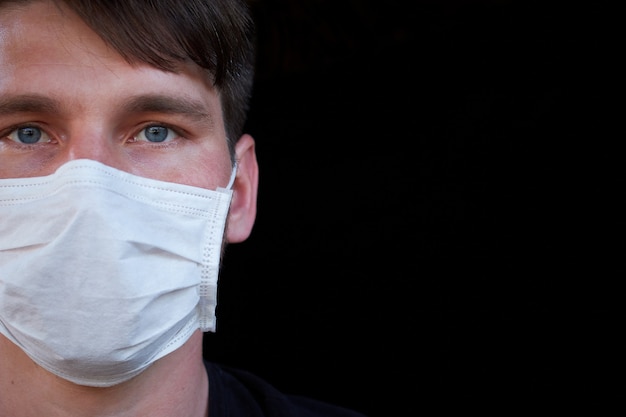 Mannetje op donkere muur in een medisch masker. Bescherming tegen virussen, bacteriën en ziekten