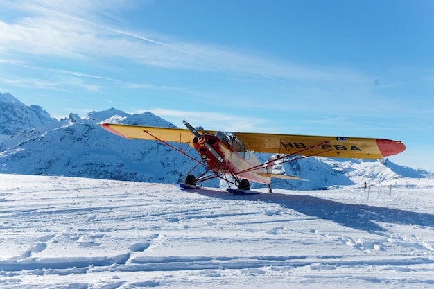 Mannlichen, Switzerland - December 31, 2013: Yellow airplane in Mountain peaks in Mannlichen in winter Swiss Alps