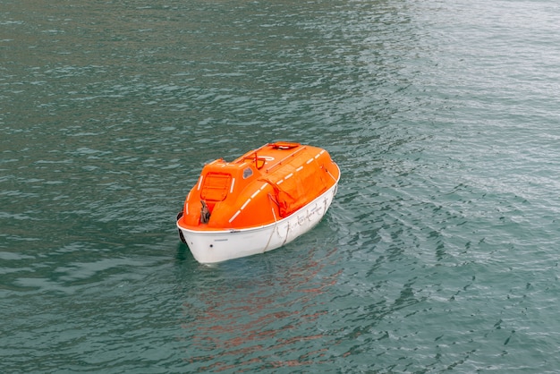 Foto manoeuvreren oranje reddingsboot in water in de arctische wateren, svalbard. schipboor verlaten. reddingsboot training. man overboord boor.