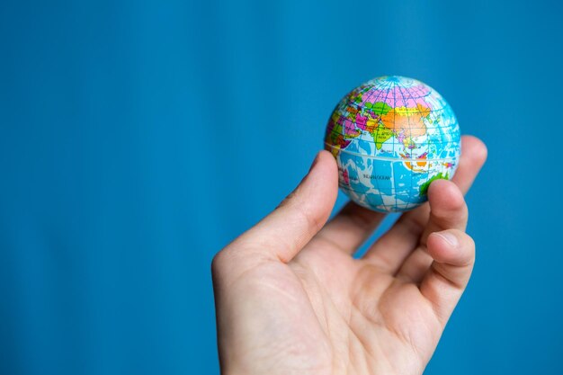 Mans adult hand holds a small globe in the palm of his hand