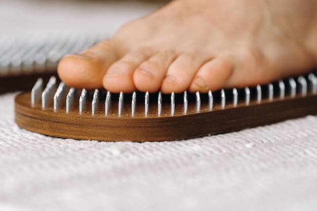 The mans feet are next to boards with nails yoga classes