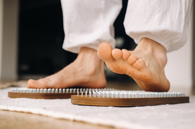 The mans feet are next to boards with nails yoga classes