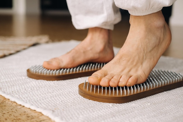 The mans feet are next to boards with nails yoga classes