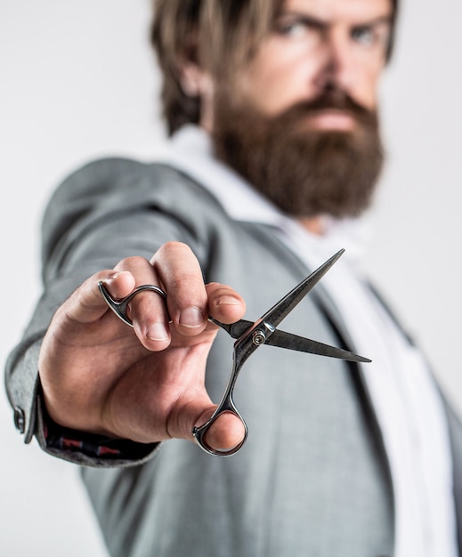 Mans haircut in barber shop. Barber scissors, barber shop. Barber scissors. Vintage barbershop, shaving. Male in barbershop, haircut, shaving. Bearded man isolated on gray background.