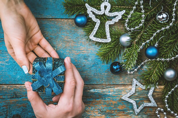 Mans hand give a gift box and womans hand take it over christmas decorated background top view