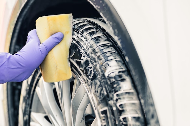 Mans hand in gloves a man washes a car wheel