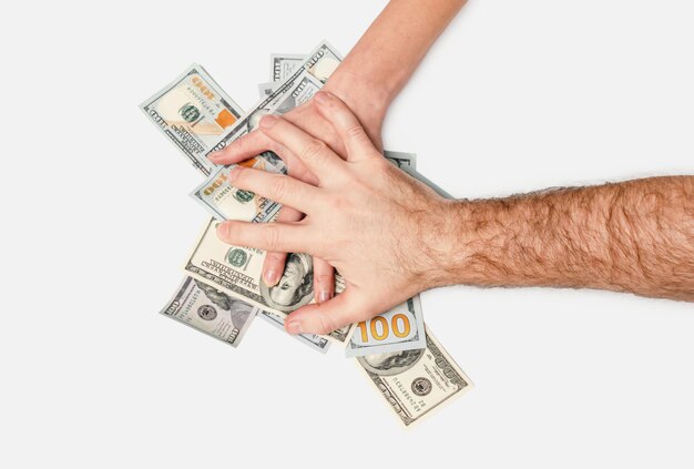 Photo mans hand grabs a womans hand on one hundred dollar bills the concept of fraud financial crimes