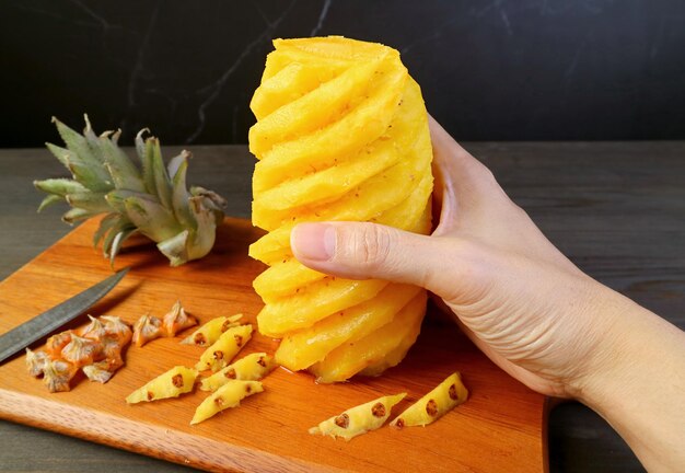 Mans hand met een verse gepelde ananas op de snijplank