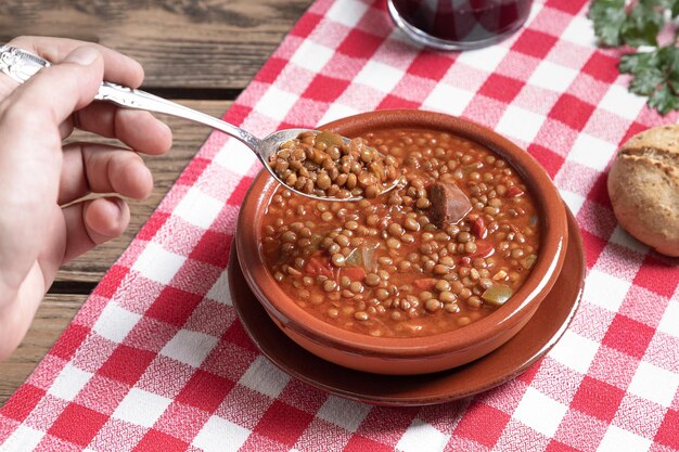 Mans hand picking up a spoonful of lentils on wooden table