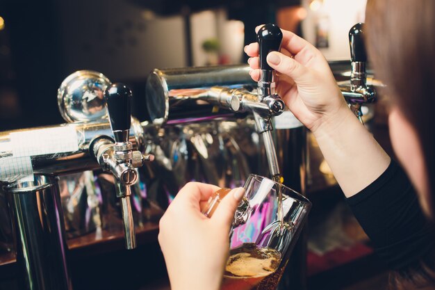 Mans hand pouring pint of beer behind the bar.