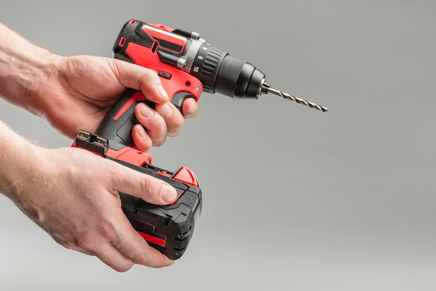 A mans hand removes the battery from a cordless tool a man\
inserts a battery into a screwdriver repa...