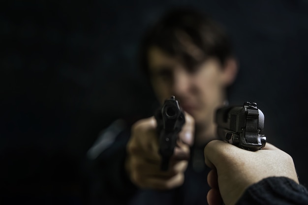 두 명의 도둑이나 살인자 총기의 리볼버 총격전으로 범인을 가리키는 권총을 든 남자의 손...