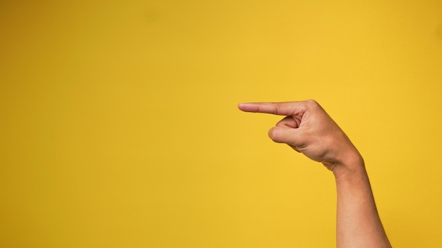Mans hand with pointing hand gesture on yellow background