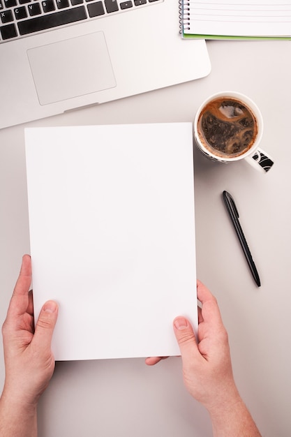 Mans handen met blanco papier op het bureau met computer en koffie