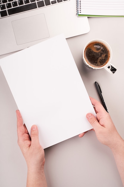 Mans handen met blanco papier op het bureau met computer en koffie