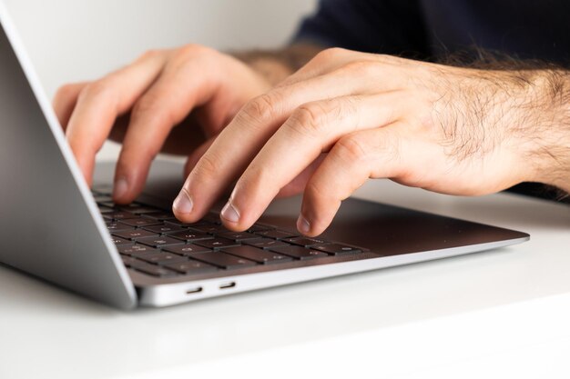 Mans handen op het toetsenbord van een computer typen van een tekst homeoffce of freelancer die thuis werkt