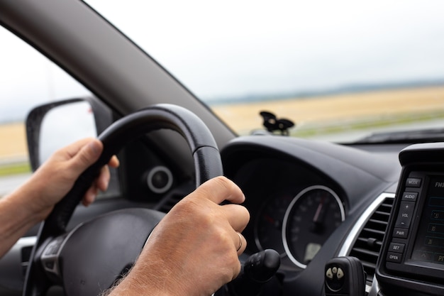 Mans hands hold the steering wheel of a car