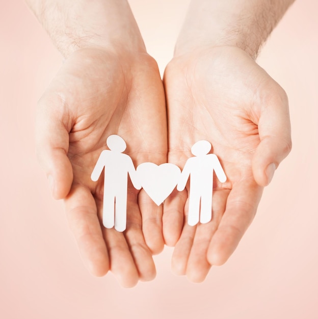 mans hands showing two paper men with heart shape