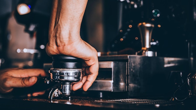 コーヒーショップでポータフィルターを持った男の手