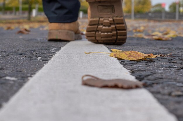 Mans hiking boots on the white line of the road close-up shot.