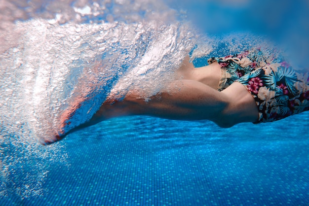 Ноги мужчины плавают под водой в бассейне летом