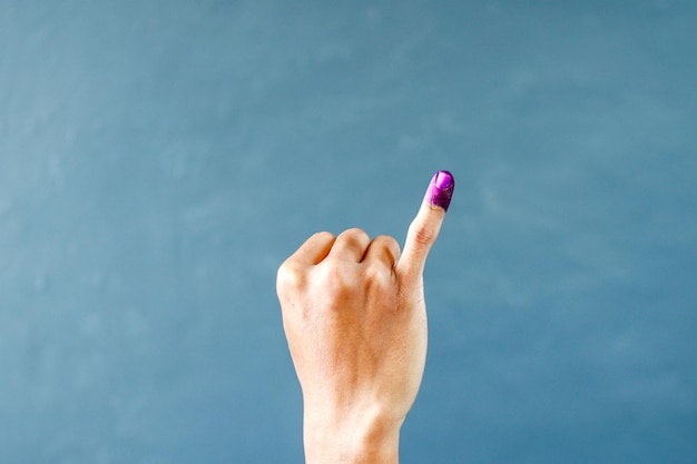 Mans little finger after voting on Indonesias presidential election on grey background