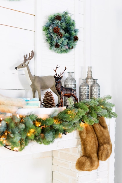 Mantelpiece with Christmas decorations. Cozy winter scene. White interior details with lights.